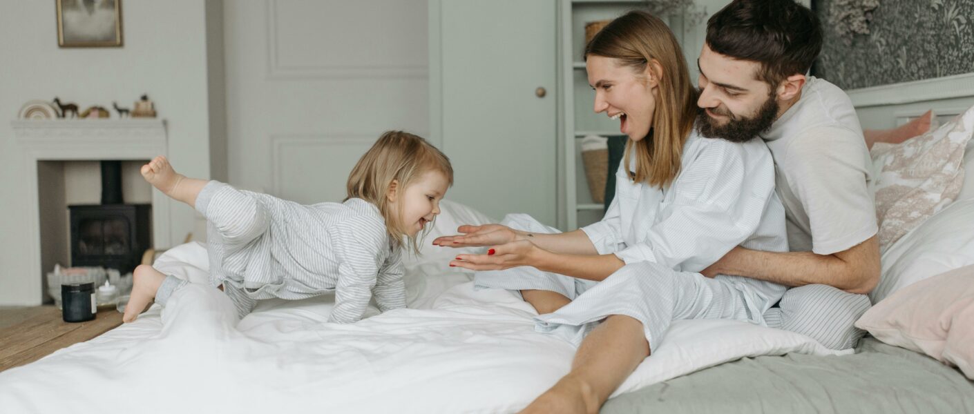 Genitori e bimba felici sul letto